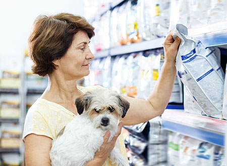 woman viewing dog food bag from shelf 